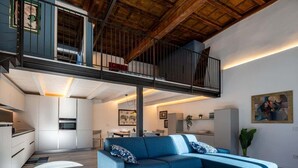 Un appartement moderne de style « loft », doté d’une mezzanine, d’un espace de vie et de salle à manger à aire ouverte, et d’une cuisine équipée d’appareils électroménagers intégrés.