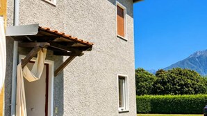 Une maison à deux étages avec une façade en pierre, une porte en bois et une petite fenêtre.