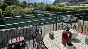 Een balkon met een tafel, stoelen en een waterkoker.