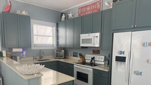Una cocina con gabinetes color turquesa, un refrigerador blanco, un microondas y una estufa.