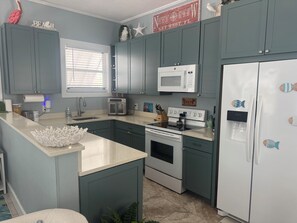 A kitchen with teal cabinets, a white refrigerator, a microwave, and a stove. - Turtle's Nest, 3 BR+3BA, dog friendly, Conch Cottage in Midtown Key West (Key West)