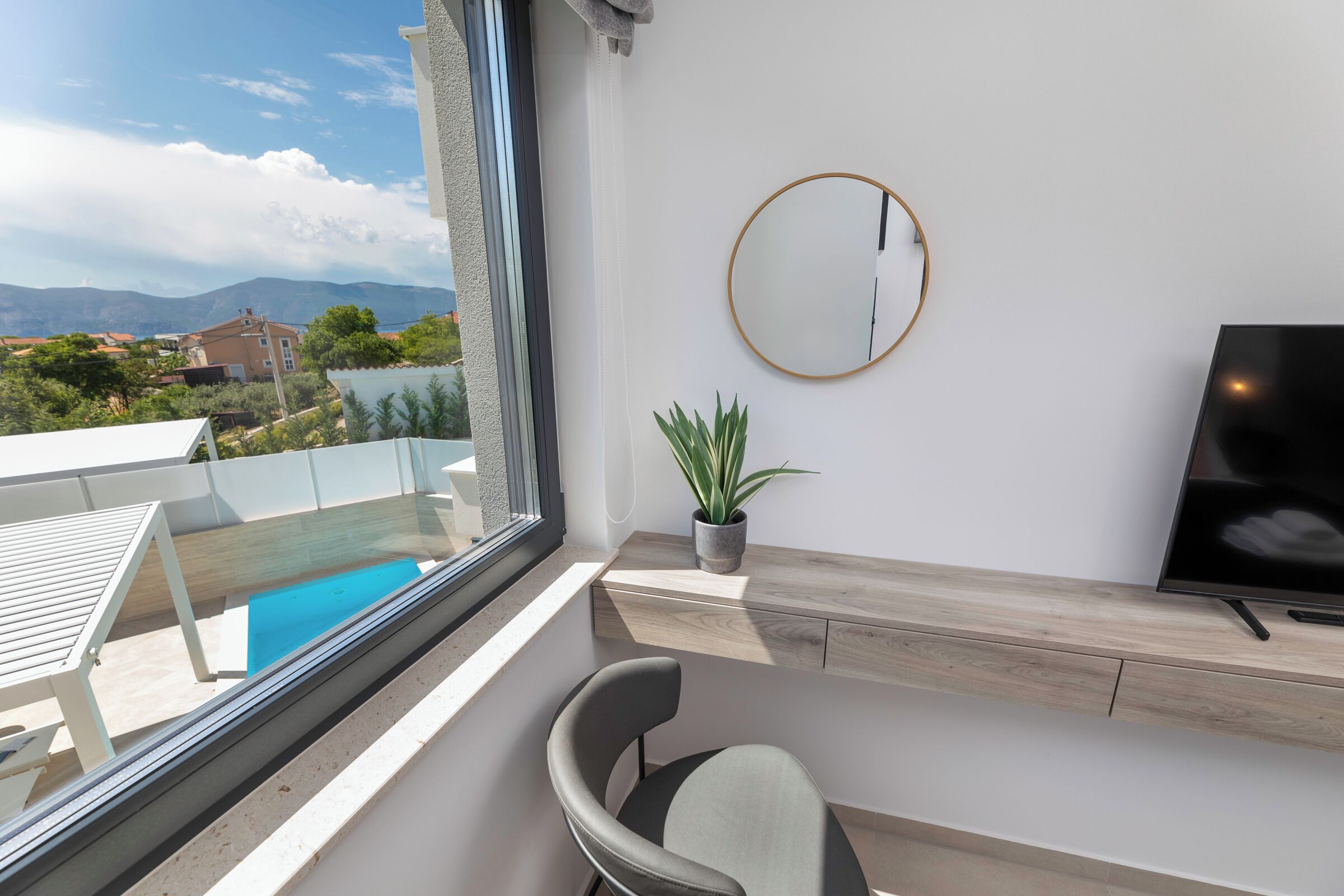 Ein Balkon mit Pool, einem Stuhl, einem Fernseher und einem Blumentopf.