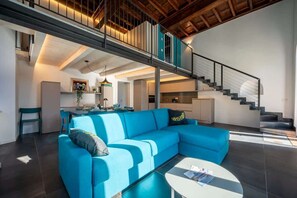 A modern living room with a blue sofa, a white coffee table, and a staircase leading to an upper level. - Ancient Gravedona - Apt Maria - Larihome A41 (Gravedona)