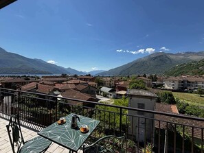 Un balcón con mesa, sillas y vistas a un pueblo y montañas.