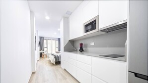 Una cocina moderna con armarios blancos, un microondas y un lavamanos.