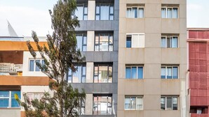 Un edificio de varios pisos con un diseño arquitectónico moderno, que combina balcones y ventanas.