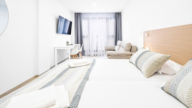 Ein modernes Hotelzimmer mit einem großen Bett, einem Schreibtisch, einem Stuhl und einem Fernseher.