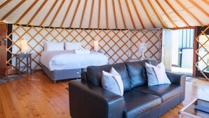 Interieur van een joert met een bed, een leren bank en een houten vloer.