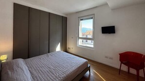 A bedroom with a bed, a window, a TV, and a red chair. - The Wave Musso - Larihome A87 (Musso)