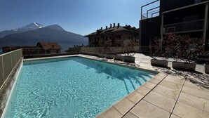 A swimming pool with a mountain view, surrounded by buildings with balconies. - The Wave Musso - Larihome A87 (Musso)