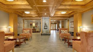 Un hall d’entrée spacieux, doté d’un plancher en bois, de canapés en cuir et d’un pilier décoratif central.