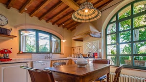 Una cocina rústica con una mesa de madera, sillas y un amplio ventanal con vistas al verdor.