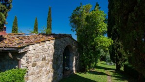 Un edificio de piedra con tejado de tejas, un arco de entrada y un camino de jardín.