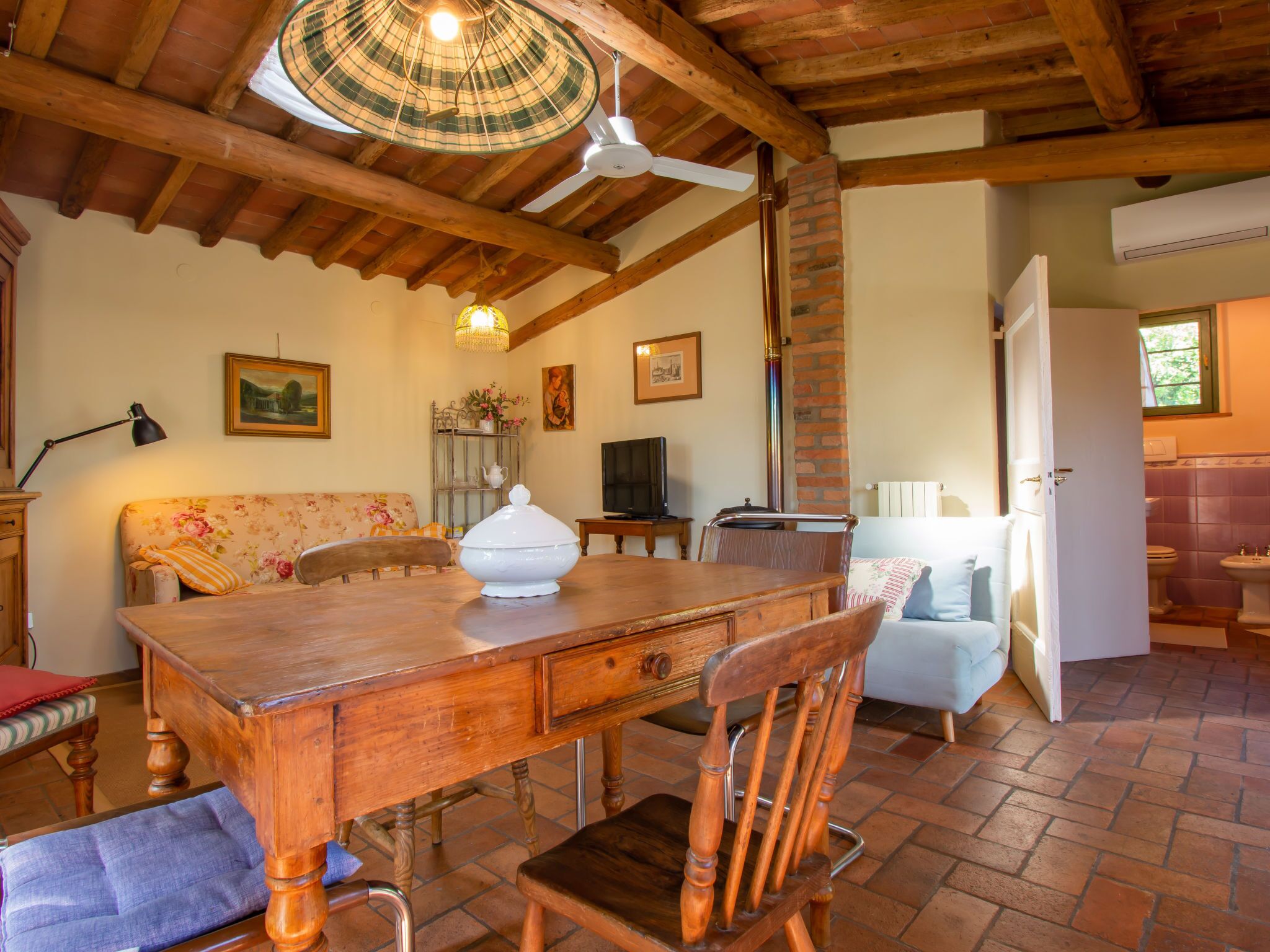 Un comedor rústico con una mesa de madera, sillas y un ventilador de techo.