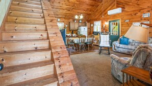 A wooden cabin interior with a staircase, dining area, and living room. - Keuka Lakefront | Dock w/ Boat Access | Kayak (Hammondsport)