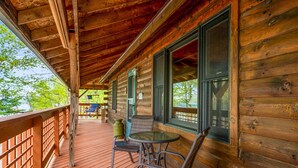A wooden cabin with a covered porch, a glass table, and chairs. - Keuka Lakefront | Dock w/ Boat Access | Kayak (Hammondsport)