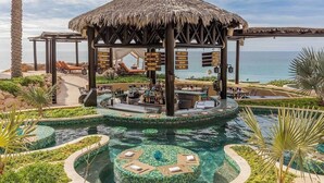 Ein Resort mit Poolbereich, Bar und einem überdachten Pavillon mit Blick auf das Meer.