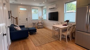 A modern kitchen with a built-in refrigerator, a dining table with chairs, and a sofa with cushions.