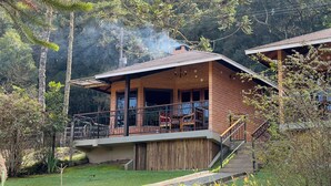 A two-story house with a balcony, surrounded by trees and a wooden fence. - Flores da Mantiqueira (Monte Verde)