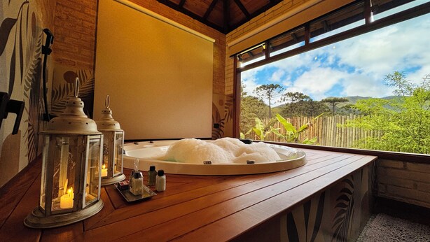 A wooden bench with a hot tub and candles. - Flores da Mantiqueira (Monte Verde)