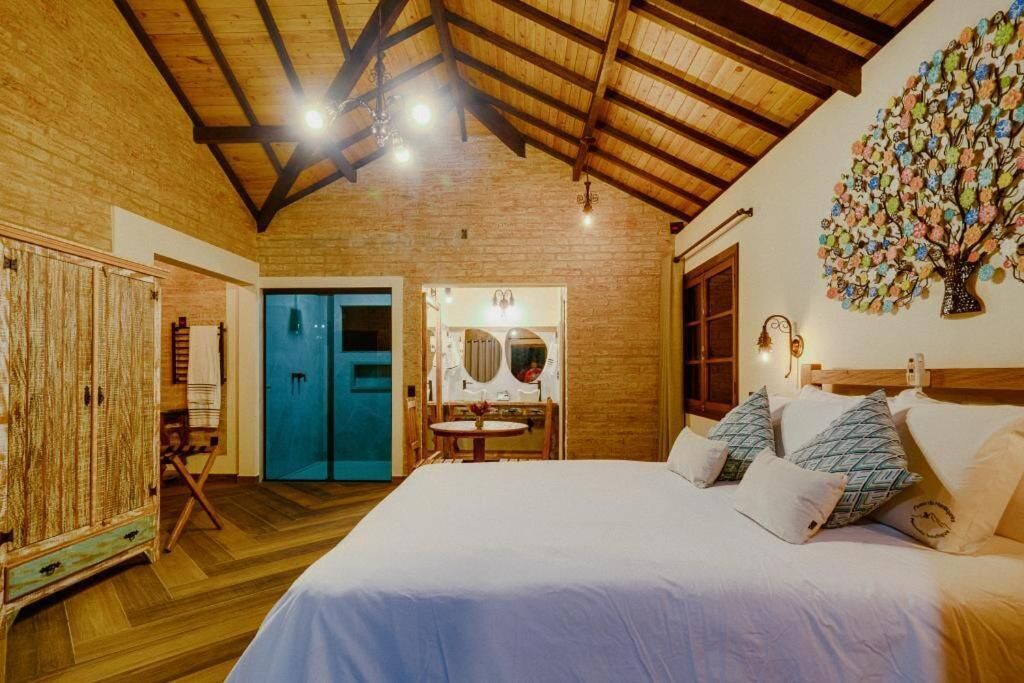 A bedroom with a large bed, wooden ceiling beams, a blue door, and a wall-mounted mirror.
