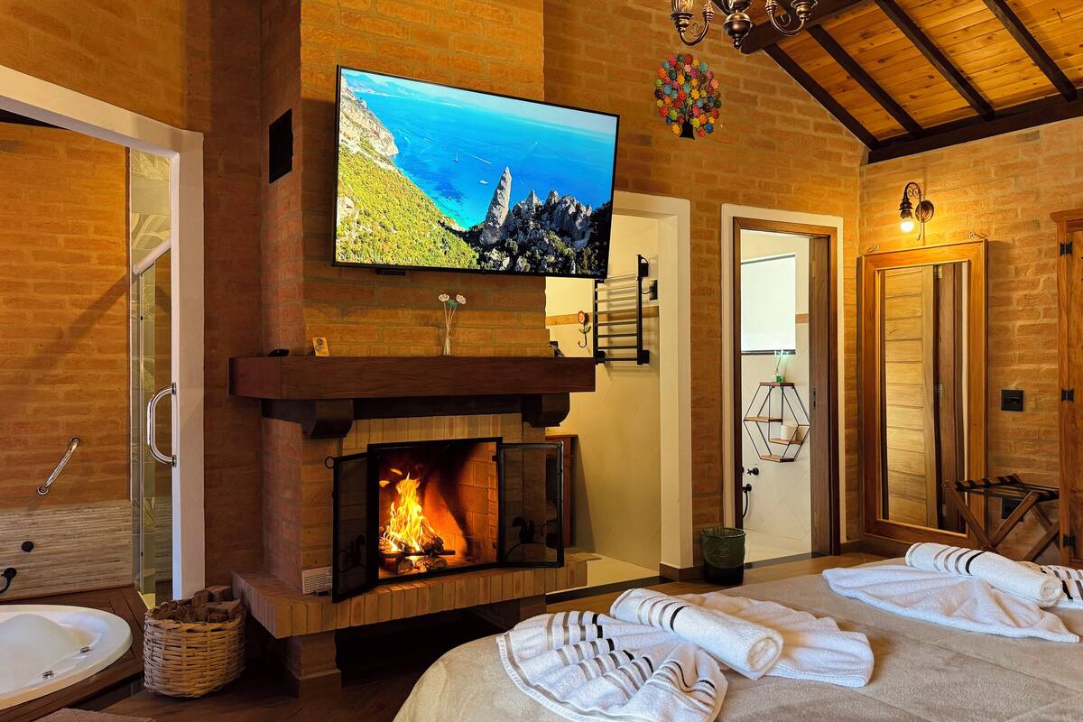 A cozy room with a fireplace, a television mounted above it, and a shower area.
