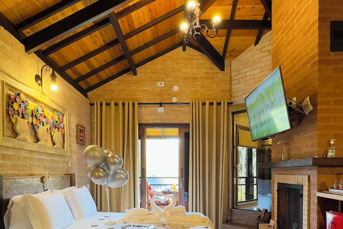A cozy room with a large bed, a fireplace, and a television.