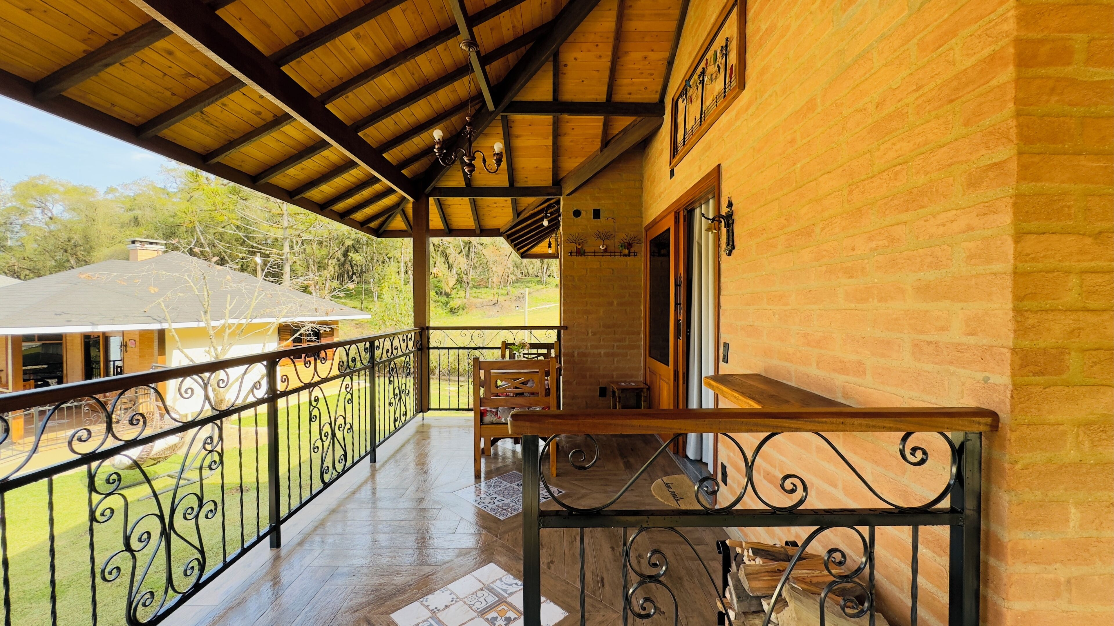 A covered balcony with a wooden railing, a table, and chairs.