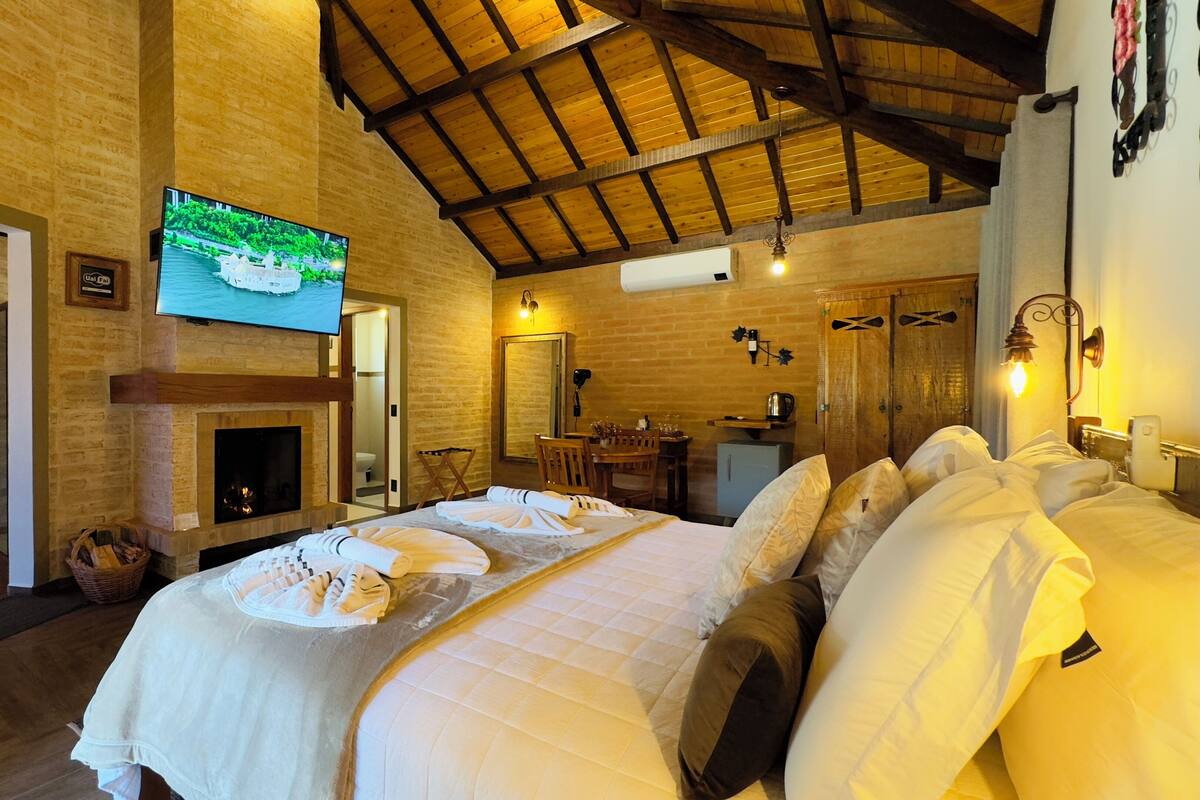 A hotel room with a large bed, a fireplace, a TV, and a bathroom.