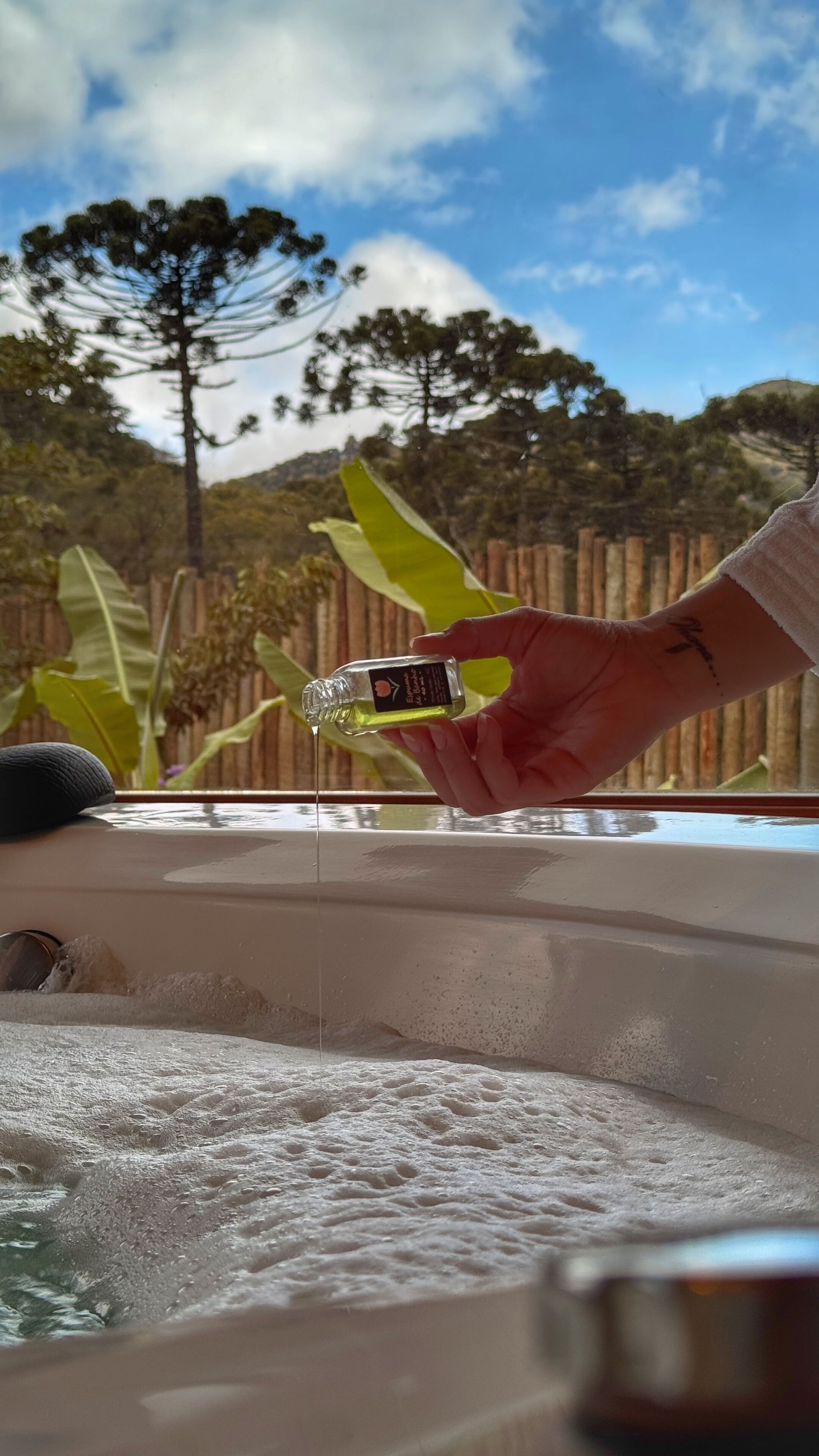 A hand pouring a liquid from a bottle into a hot tub.
