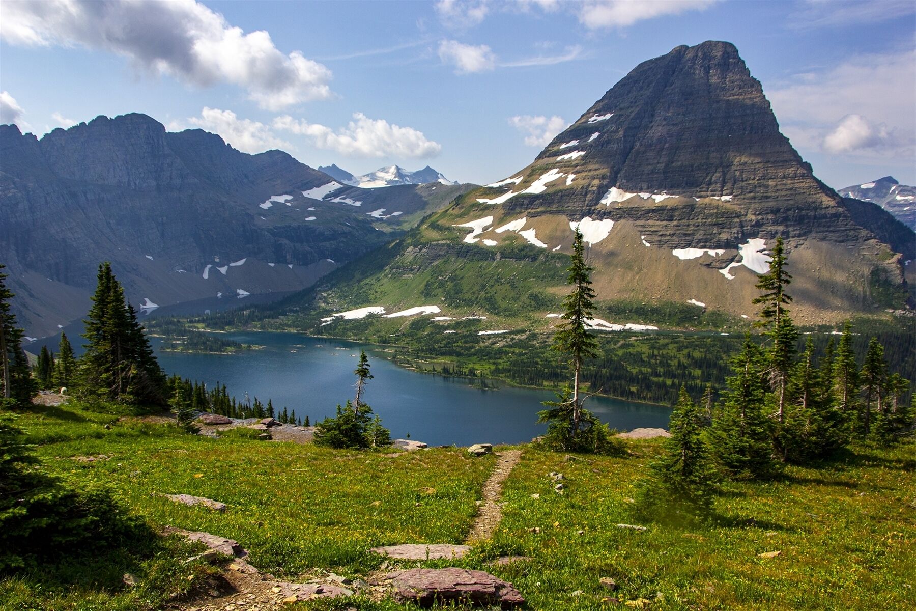 A mountain landscape with a lake, trees, and a clear sky.