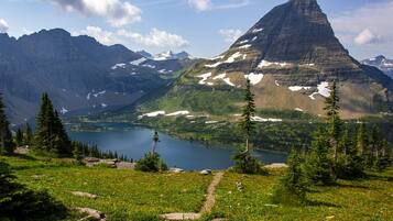 A mountain landscape with a lake, trees, and a clear sky.
