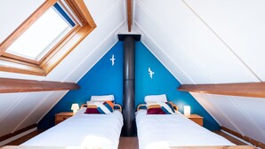 Une pièce avec deux lits en bois, un radiateur noir et une lucarne.