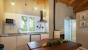 A modern kitchen with white cabinets, a microwave, a stove, and a window with greenery visible outside.