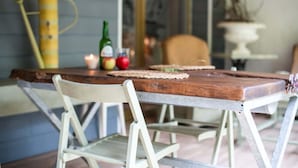 A rustic dining table with a wooden top and metal legs, accompanied by a white chair.