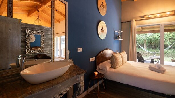 Une chambre à coucher avec un grand lit, une tête de lit en bois, une table de chevet et un grand miroir.
