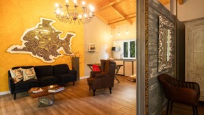 Un salon avec un canapé noir, une table basse en bois et un lustre.