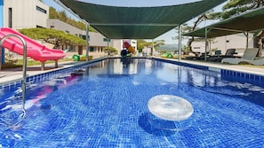 A swimming pool with a slide, lounge chairs, and a shaded area. - Gyeongju Ain Kids Pool Villa (Gyeongju)
