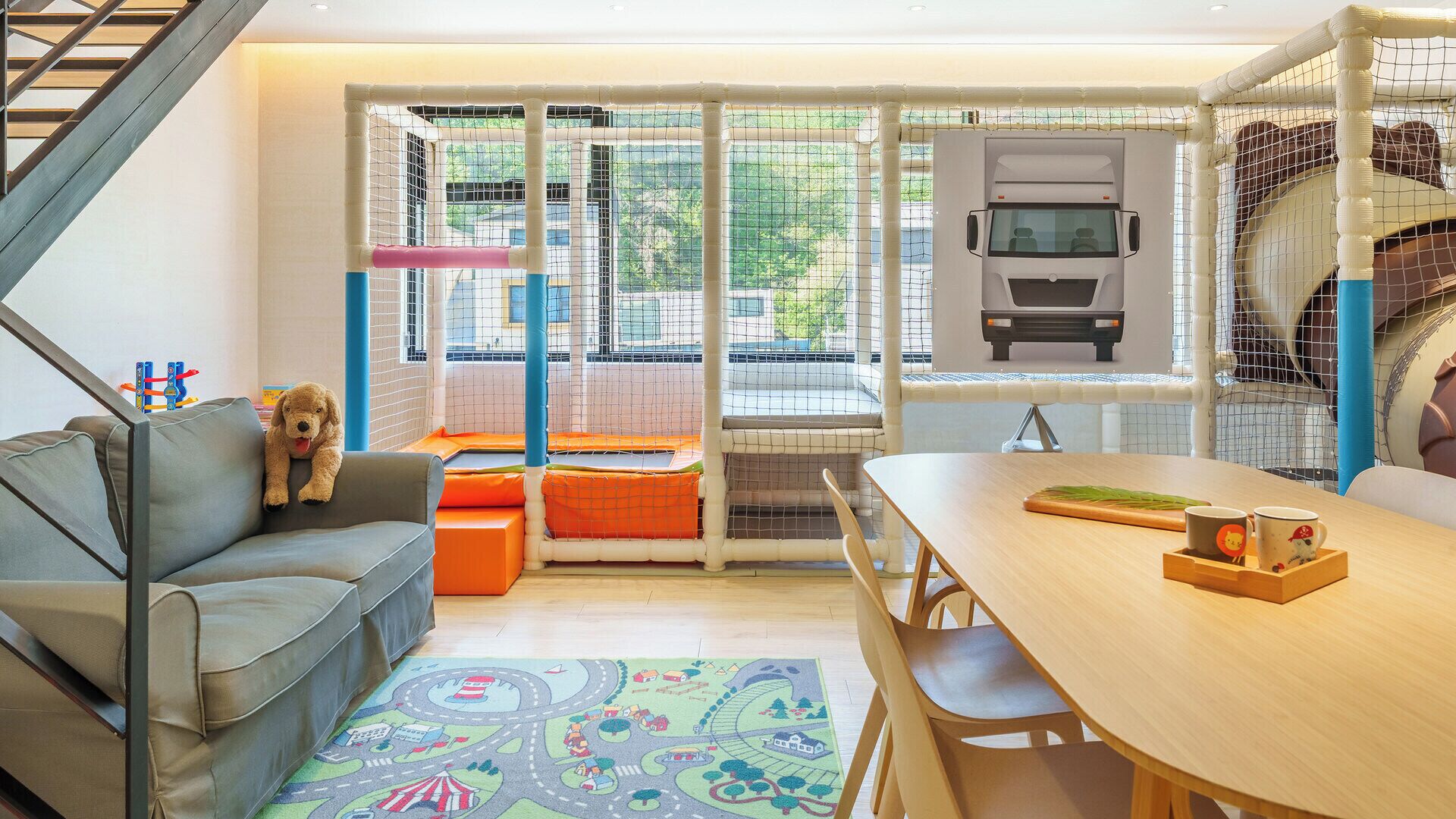 Een gezellige woonkamer met een bank, een eettafel en een kinderpoort voor huisdieren.