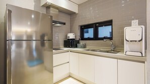 Una cocina moderna con un refrigerador de acero inoxidable, una cafetera, un microondas, un lavamanos y un dispensador de agua RuHens.