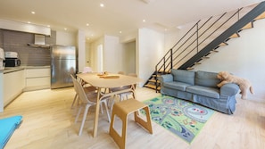 A modern interior with a dining area, kitchen, staircase, and a sofa with a dog. - Gyeongju Ain Kids Pool Villa (Gyeongju)