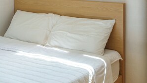 Un lit avec une tête de lit en bois et une literie blanche.