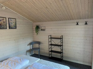 Ein Zimmer mit einem Bett, einem Sessel, einem Regal und zwei Bildern an der Wand.