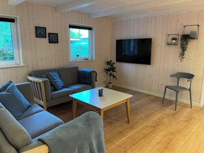 Ein Wohnzimmer mit einer Couch, einem Couchtisch, einem Fernseher und einem Sessel.