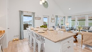 A spacious kitchen with a large island, bar stools, and a dining area with a view. - Steps to the Beach l Pool l Tiki Bar & Pet-Friendly (Crystal Beach)