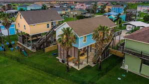 A residential area with houses, a playground, and a large blue house with a deck. - Steps to the Beach l Pool l Tiki Bar & Pet-Friendly (Crystal Beach)