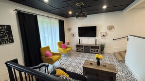 A modern living room with a black and white patterned floor, a black ceiling, and a staircase with a black railing.