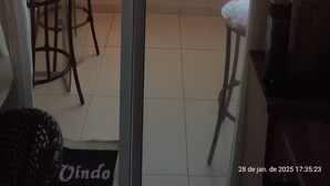 Un balcón con puerta de vidrio, una mesita con una silla y una planta en maceta.