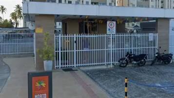 A hotel entrance with a wheelchair-accessible parking space, a sign for 'Horto da Barra', and a gated parking area.