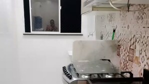 Una cocina compacta con baldosas blancas, cocina a gas y microondas.